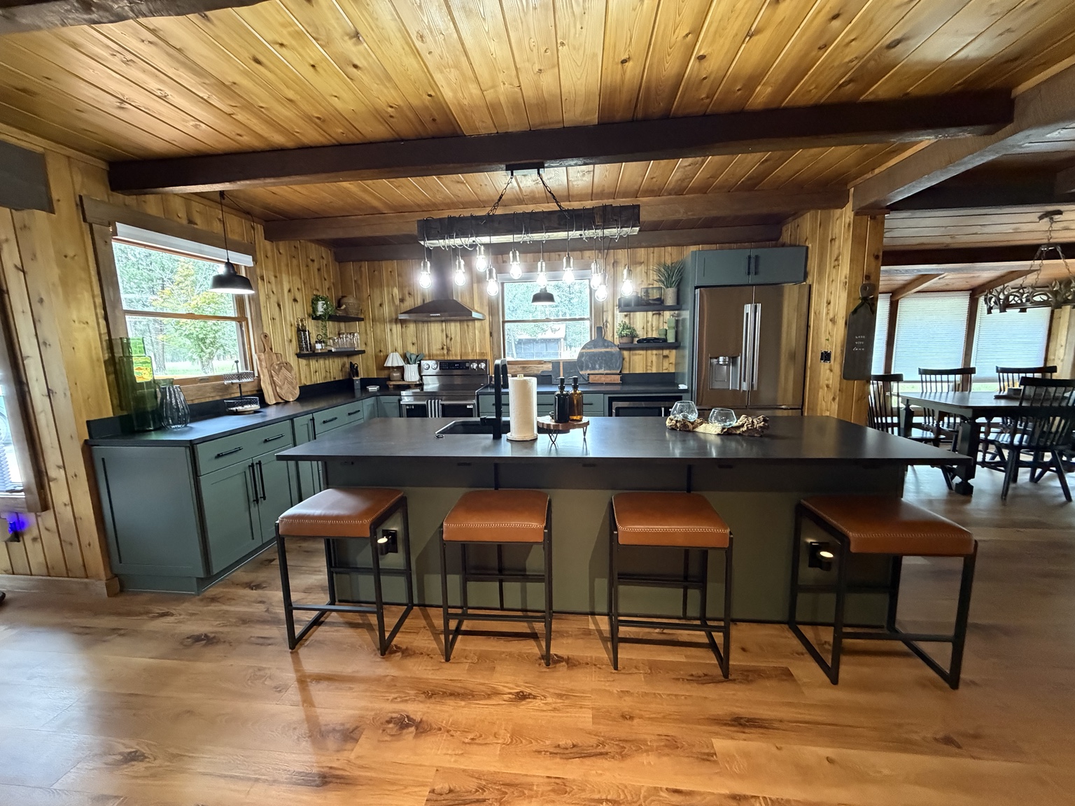 Finished custom kitchen with green cabinetry, wood ceiling, and large island
